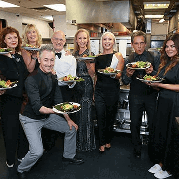 Celebrities posing for a picture each holding up plates of food