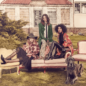 3 models sitting on a couch outside with a dog in the front